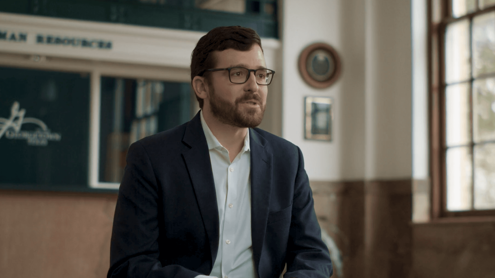 Man wearing glasses speaking during an interview in a bright interior